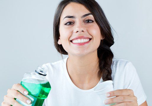 Woman smiling and holding mouthwash