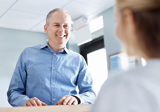 Man smiling at dental reception desk